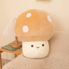 A soft, round, tan mushroom plush pillow with white spots rests on a beige textured fabric.