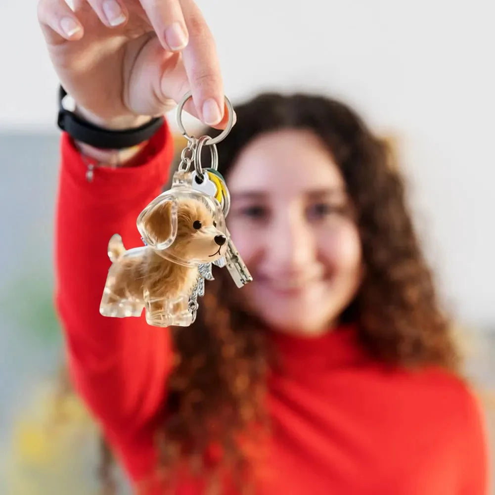 A woman holds up a dog-shaped pet hair keepsake keychain with a gold-colored charm.