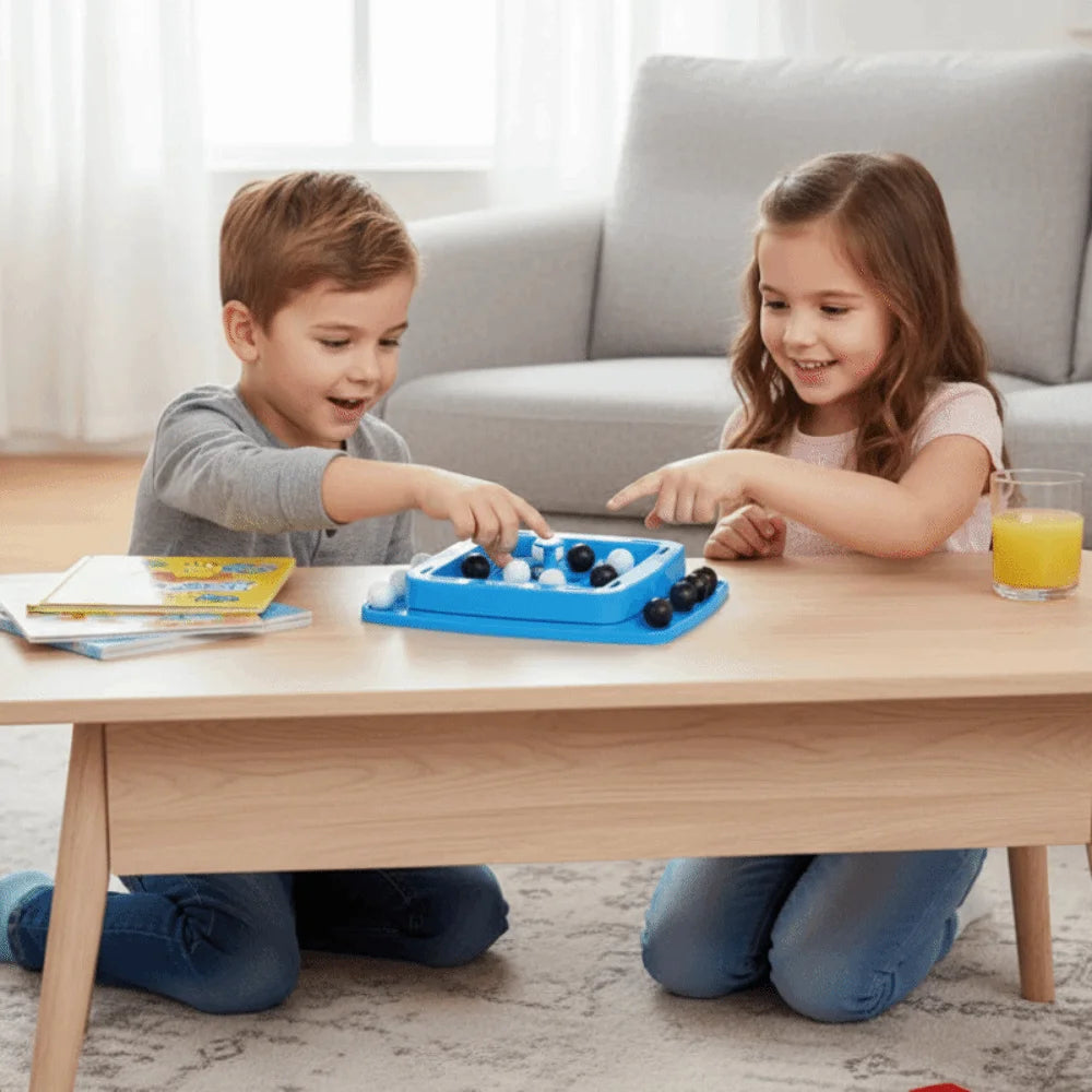 Two children play a blue strategy board game with black and white pieces on a wooden table.