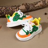A pair of green and orange casual sneakers with white soles and hook-and-loop straps resting on a brown surface.