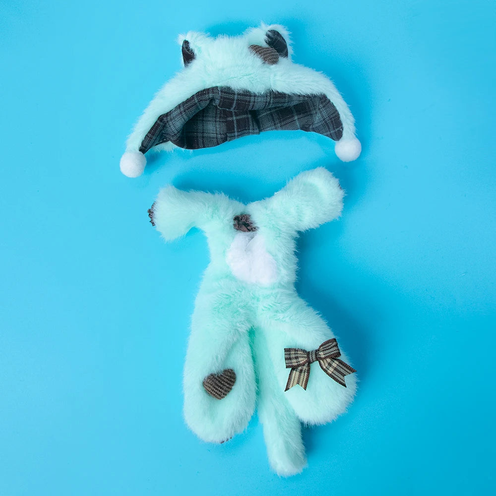 A light blue faux fur doll with a plaid hood and bow, displayed against a bright blue background.