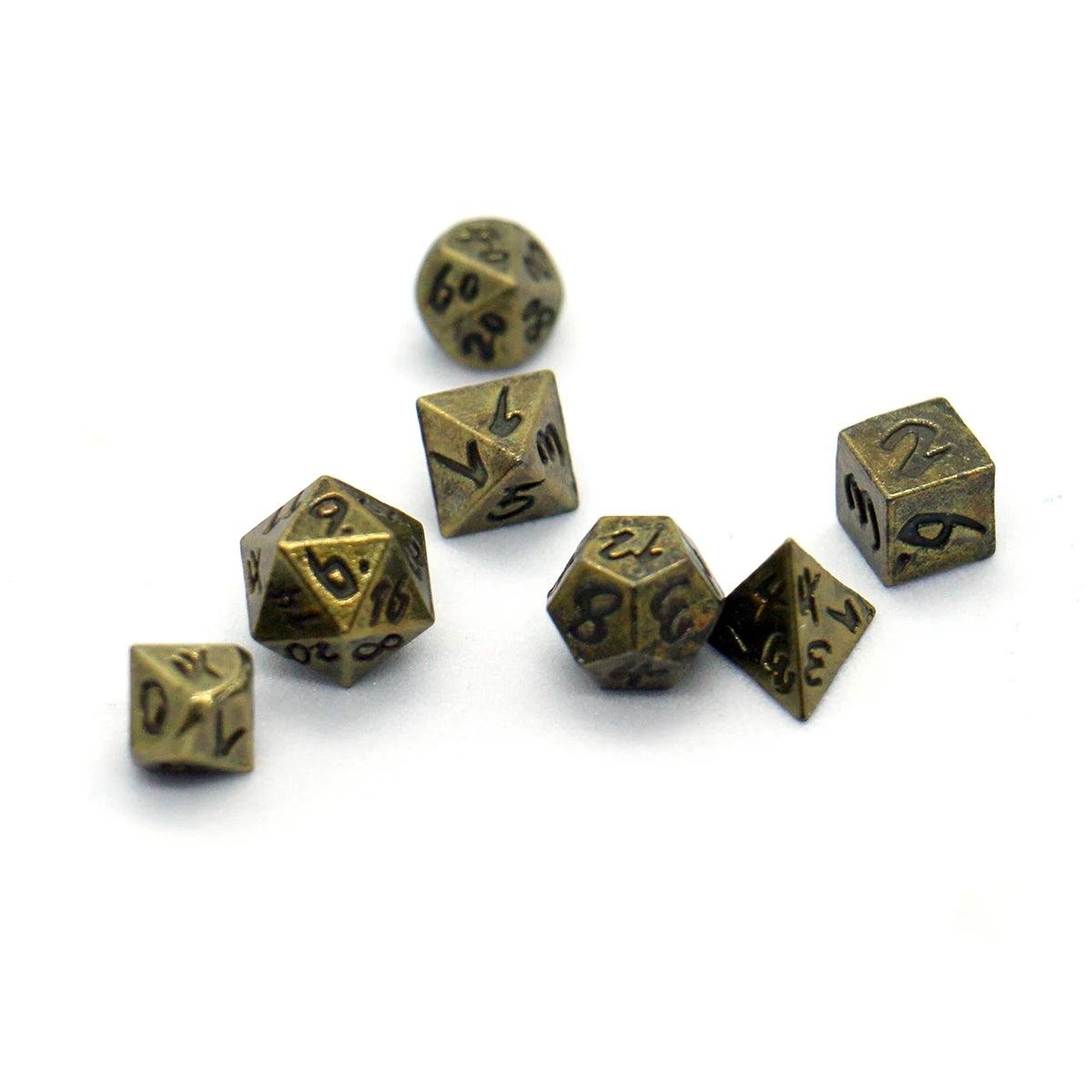 A collection of seven antique metal polyhedral dice, including a d6 and d10, scattered on a white surface.