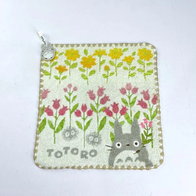 A soft stuffed animal featuring a cute gray cat design on a light green fabric with yellow and pink floral patterns.