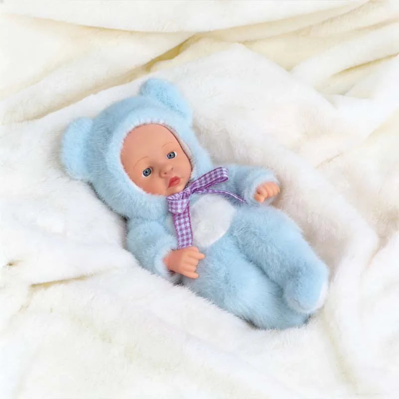 A realistic soft vinyl reborn baby doll wearing a light blue hooded outfit lying on white fur fabric.