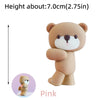 A light brown pink bear cake topper with a white snout and pink accents.