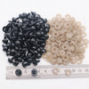 A collection of black and beige plastic safety eyes for amigurumi with locking washers displayed on a ruler.