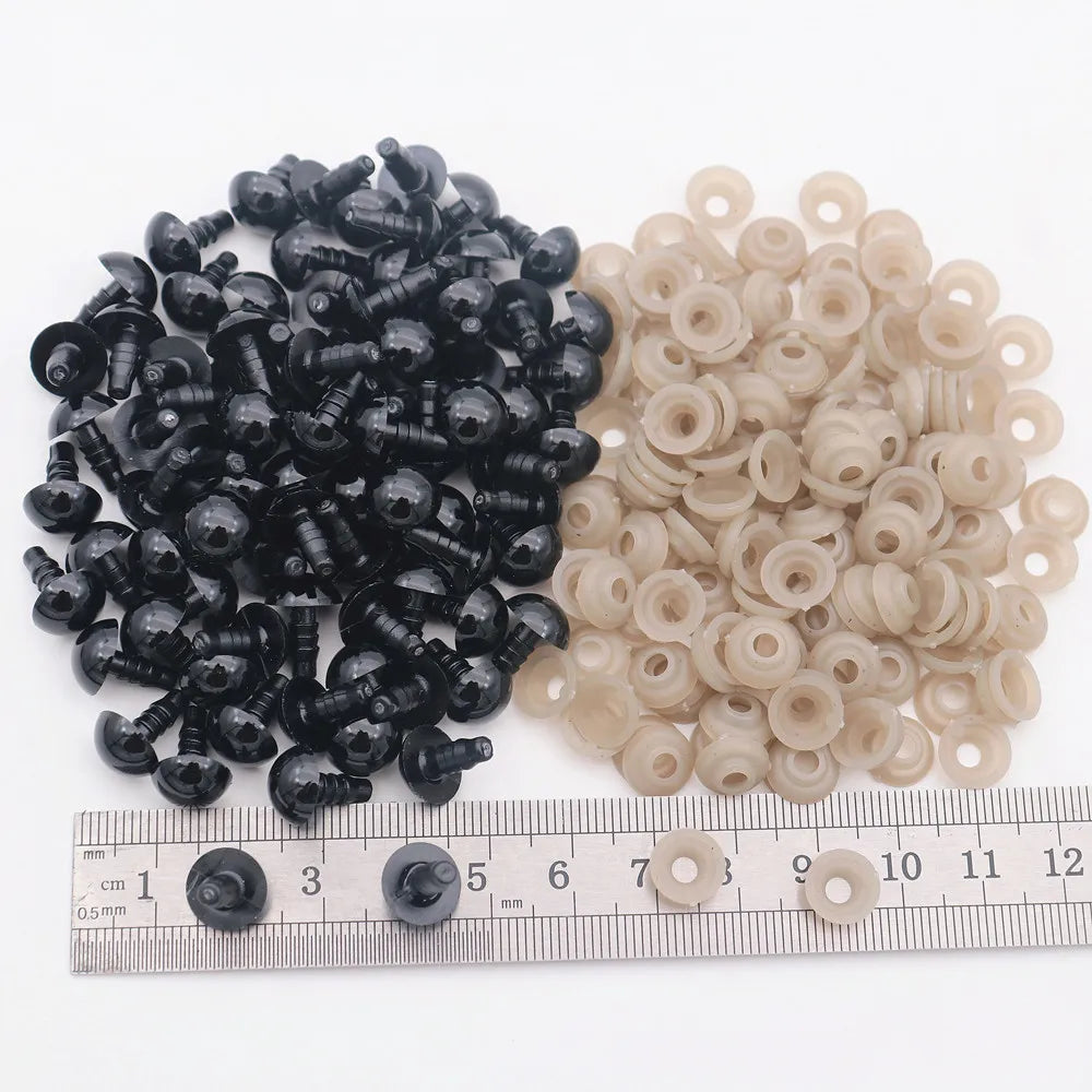A collection of black and beige plastic safety eyes for amigurumi with locking washers displayed on a ruler.