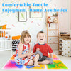 A boy and a girl sit on a colorful liquid sensory play mat indoors.