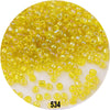 A close-up view of loose, colorful round glass seed beads in various shades of yellow and green.