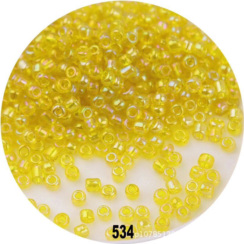 A close-up view of loose, colorful round glass seed beads in various shades of yellow and green.