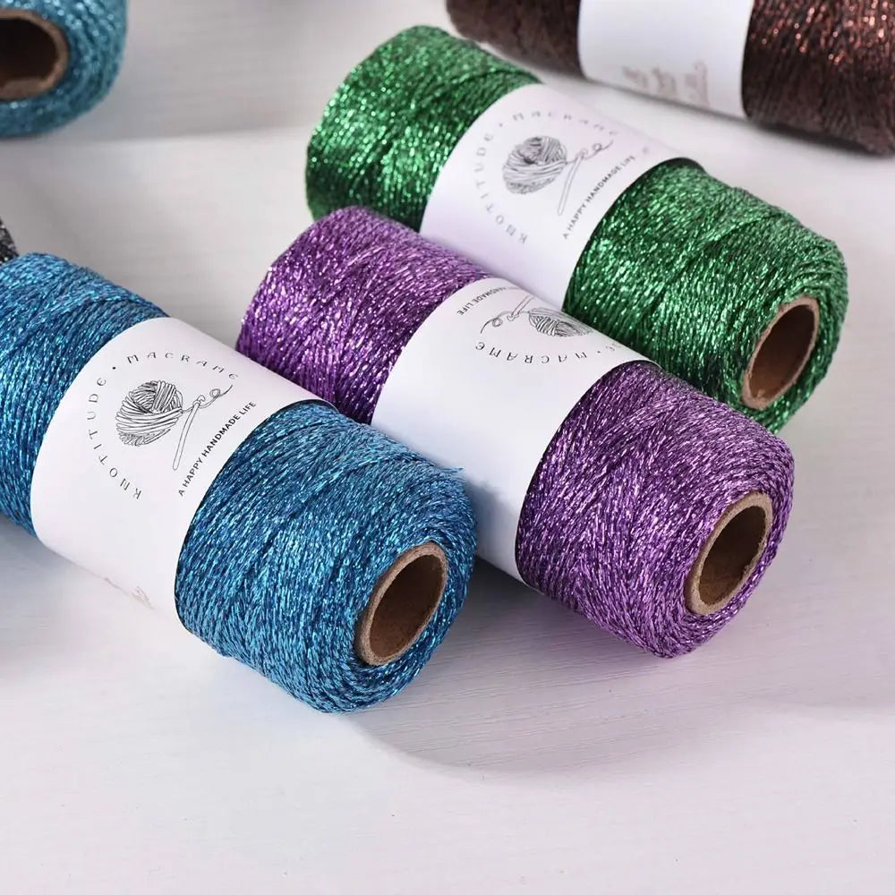 Rolls of metallic glitter yarn in green, purple, and blue thread for knitting and crochet projects