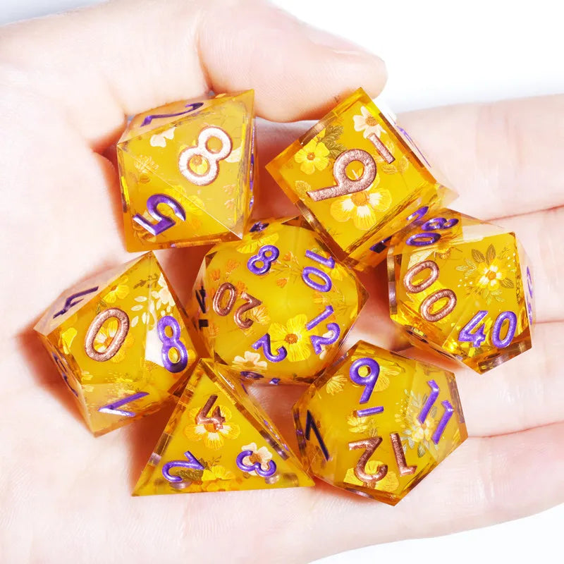 A hand holds a set of yellow resin polyhedral dice showing various numbers and symbols.