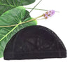 Black stretchable mesh wig cap resting on a green tropical leaf with a purple flower.
