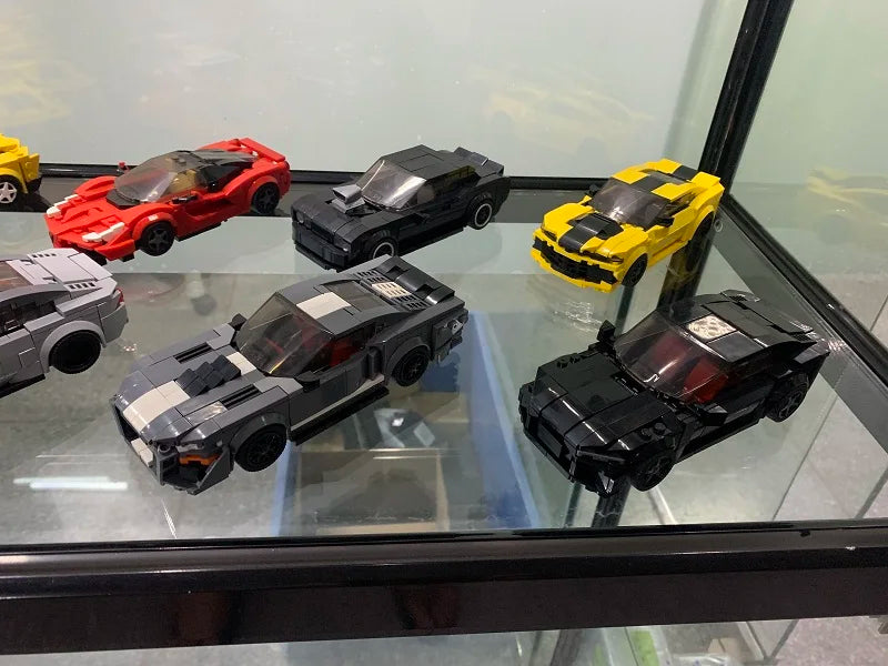 A collection of various die-cast or model cars in red, black, and yellow colors displayed in a glass case.
