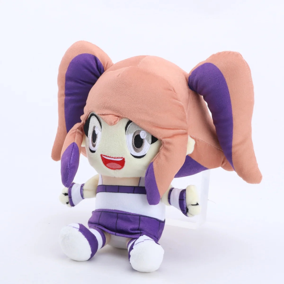 A soft collectible doll plush toy with pink hair and purple clothing.
