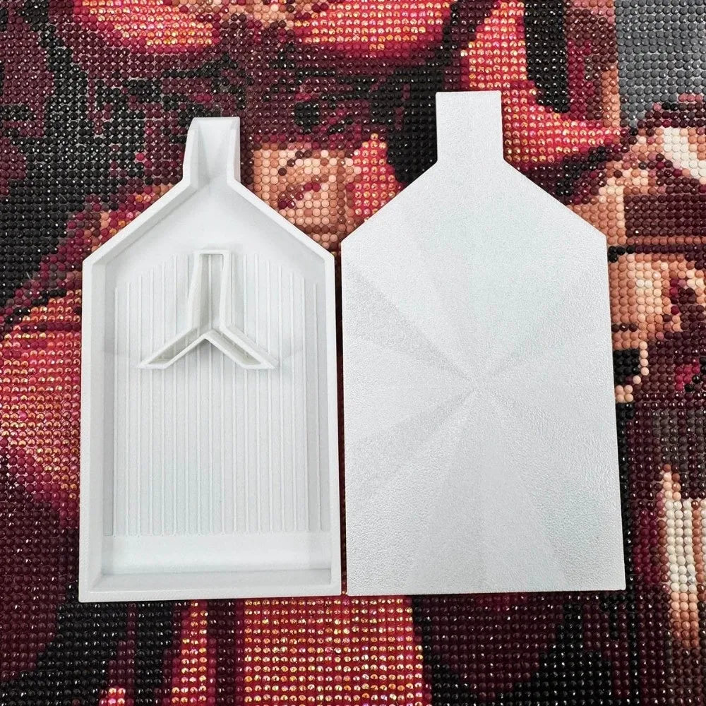 A pair of white diamond painting trays with pop-up plugs for bead sorting displayed on a dark background.
