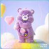 A purple Care Bear figurine holding a heart-shaped charm against a light purple background.