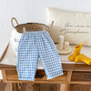 Light blue and white plaid casual pants with an elastic waist displayed on a wooden table.