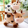 A soft, cuddly plush toy of a cow with white and brown markings and pink accents.