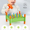 A toddler is playing with a green and orange toy hammer set for fine motor skills and color sorting.