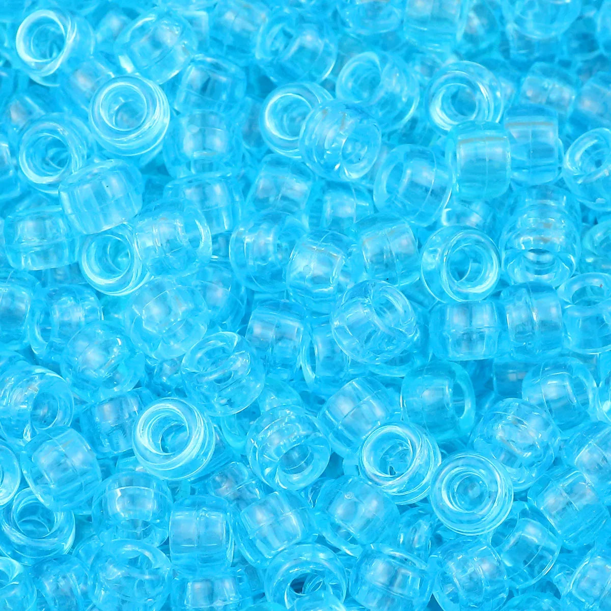 A pile of small, clear blue pony beads for jewelry making and crafts.