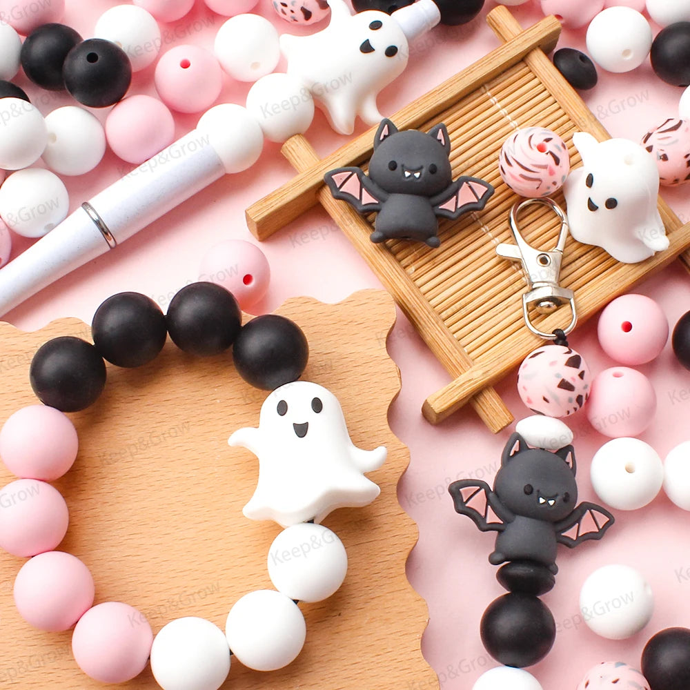 A collection of pink and white silicone crafting beads arranged on a wooden tray with a black cat silhouette.