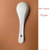 A white, elongated, spoon-shaped tool with a hole at the bottom is shown against a brown background.