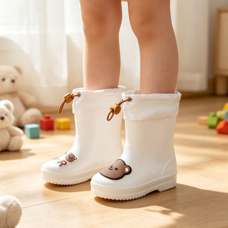 A pair of white waterproof bear rain boots for a child standing on a wooden floor.