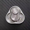 A silver metal fidget slider with a textured, oval design resting on a dark surface.