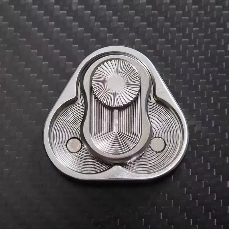 A silver metal fidget slider with a textured, oval design resting on a dark surface.
