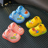 A collection of colorful children's plastic clogs in blue, yellow, and pink resting on a dark surface.