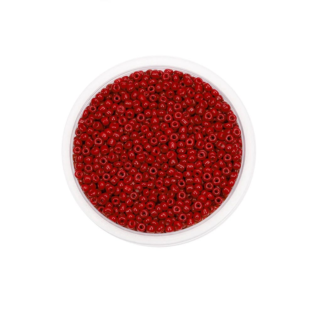 A clear plastic container filled with small, round, red glass seed beads for jewelry making.