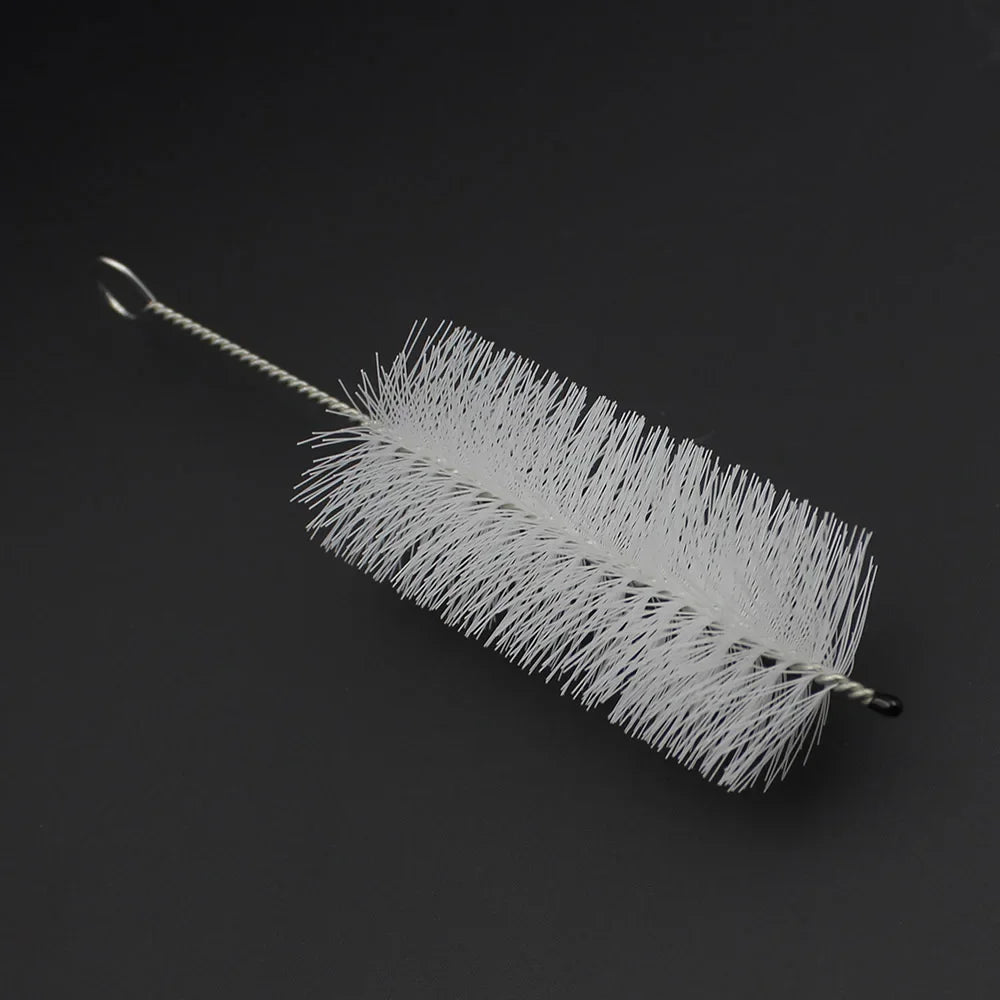 A white trumpet and cornet cleaning kit with piston and mouthpiece brushes lying on a dark surface.
