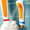A white and orange bath toy is shown spraying water from a dispenser into a white bowl.