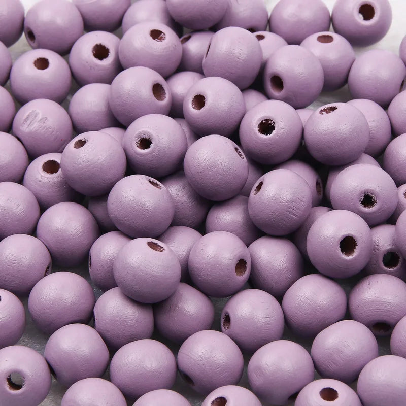 A pile of small, natural wooden beads in a light purple color.