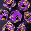 A collection of handmade liquid core resin dice set in purple and gold, showing various numbers and symbols.