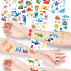 Hands display colorful glitter mermaid temporary tattoos featuring various underwater sea creatures and marine life.