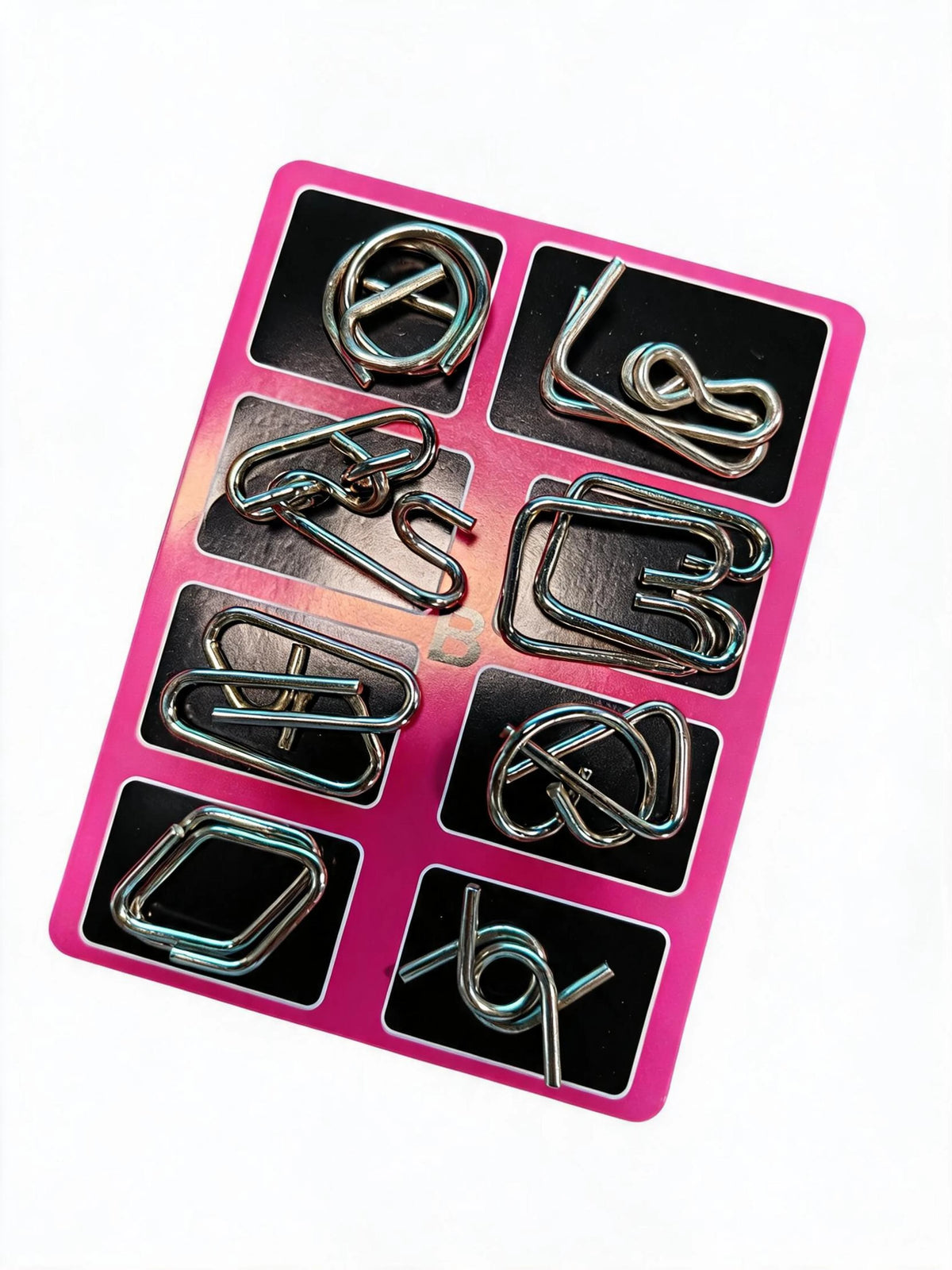 A pink plastic tray holding eight small metal brain teaser puzzle pieces.