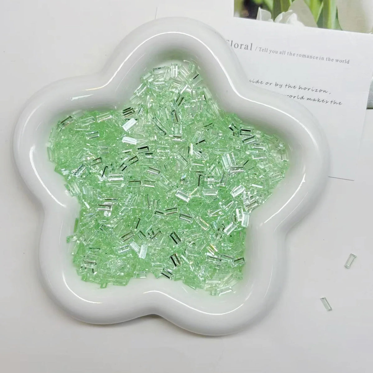 A white silicone mold filled with green acrylic ice strips for nail art and DIY crafts