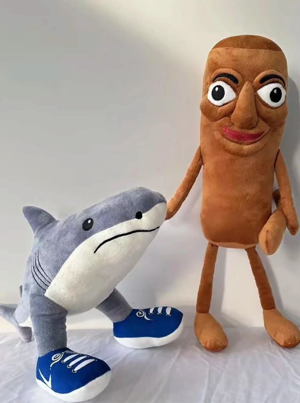 A plush toy of a shark and a humanoid figure with a brown face and body.
