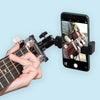A hand plays a guitar while it is mounted on a phone for live streaming or recording.