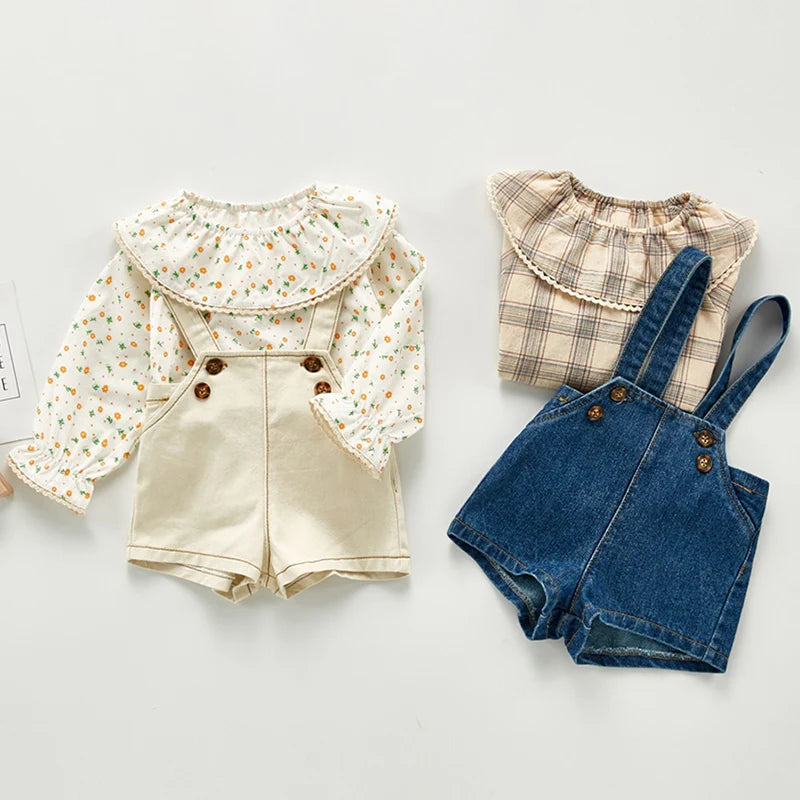 A set of toddler denim rompers featuring a light beige top with floral details and dark blue denim bottoms.