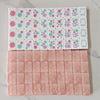 A set of pearl pink acrylic American Mahjong tiles arranged in two rows.