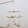 Handmade felt baby mobile featuring clouds and a moon design suspended by thin strings.
