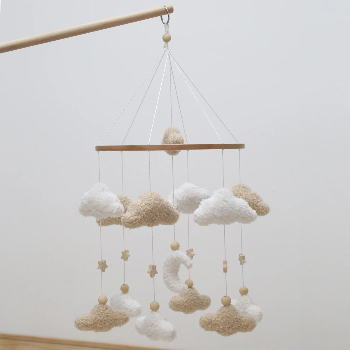 Handmade felt baby mobile featuring clouds and a moon design suspended by thin strings.