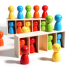A collection of colorful wooden figures in various colors arranged on a light-colored wooden shelf.