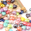 Multicolor 10mm heart-shaped acrylic beads for jewelry making displayed on a bamboo stick.