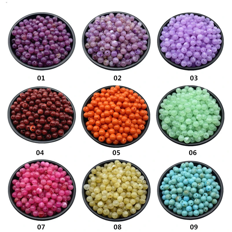 Nine bowls of acrylic round beads in various colors including purple, orange, green, pink, and blue for jewelry making