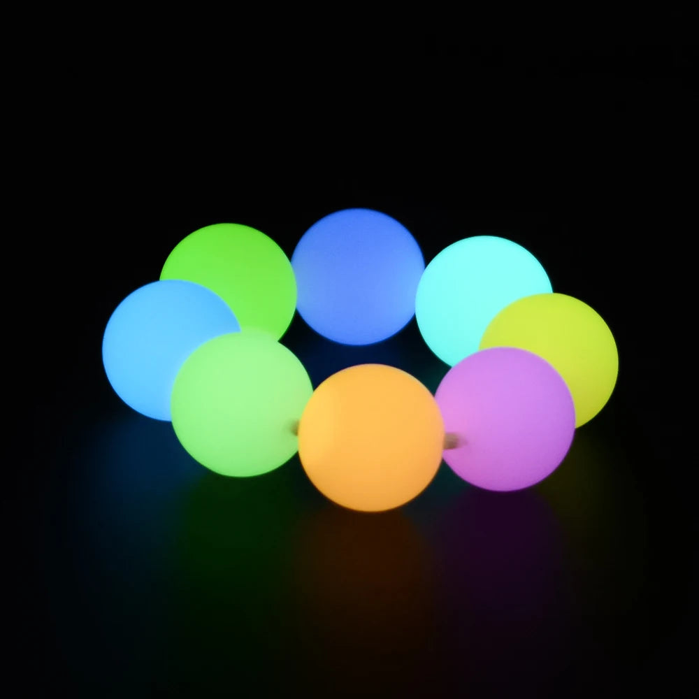 A cluster of glowing silicone beads in various colors, including green, blue, yellow, and purple, against a black background.