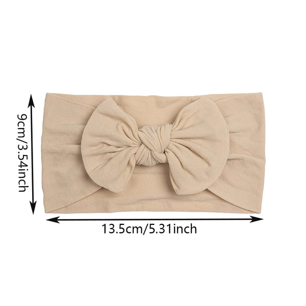 Beige Baumwoll-Baby-Haube mit Schleifenverzierung, flach dargestellt.